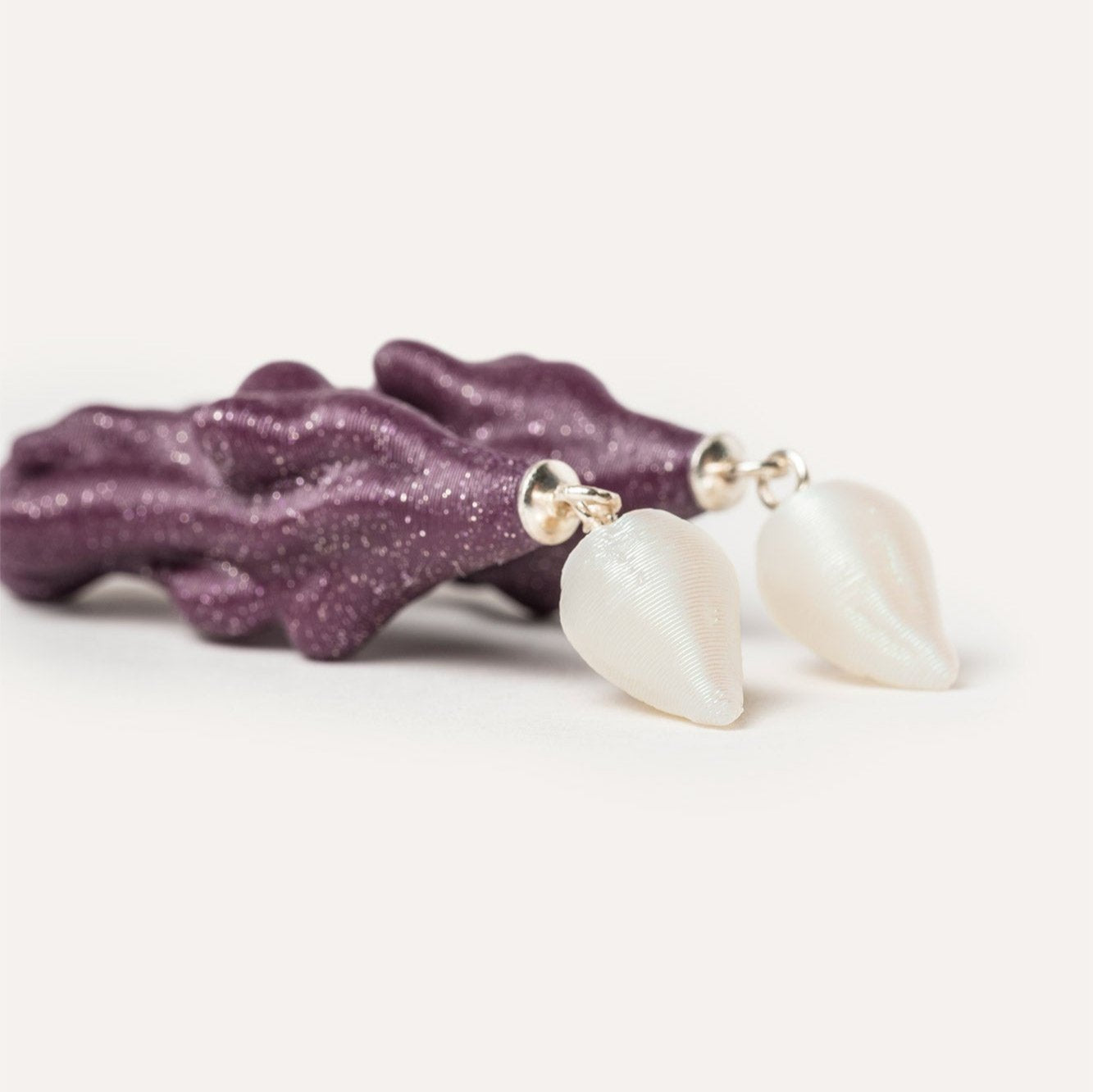 Detalle de pendientes largos color morado con forma organica